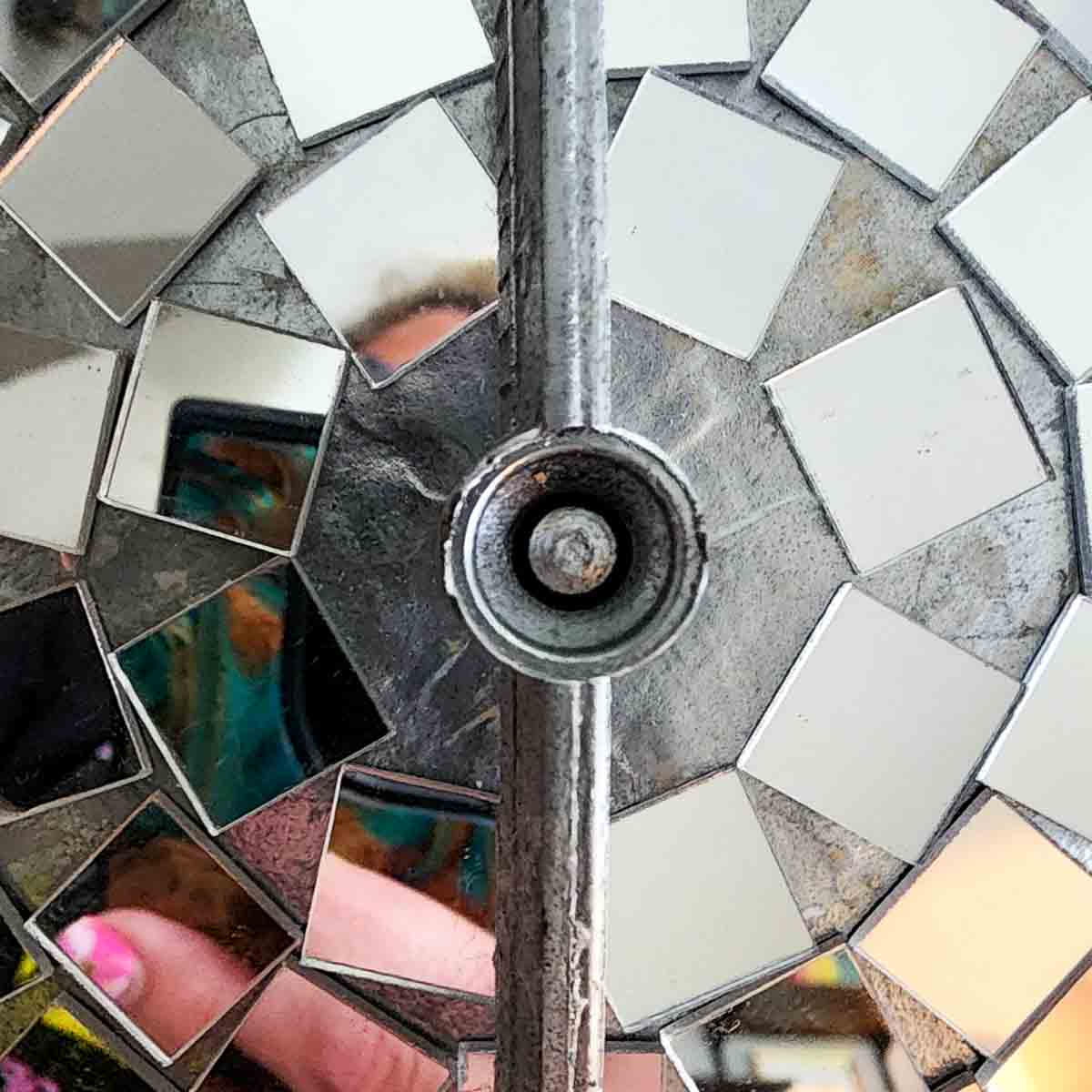 Applying mirror mosaic tiles to a globe for a DIY disco ball.